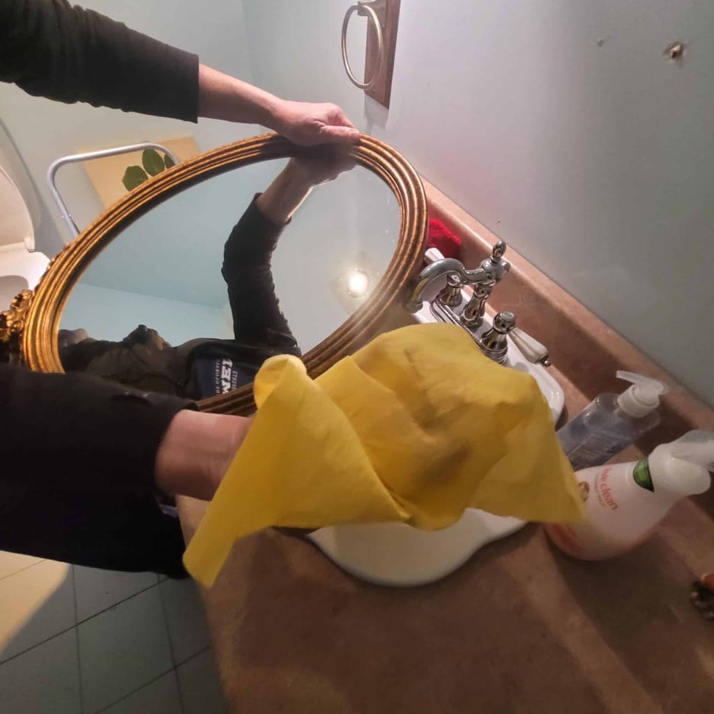 Personne qui nettoie un mirroir dans une salle de bain